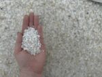 Белая плосковидная мраморная крошка 2–5 мм крупным планом в руке